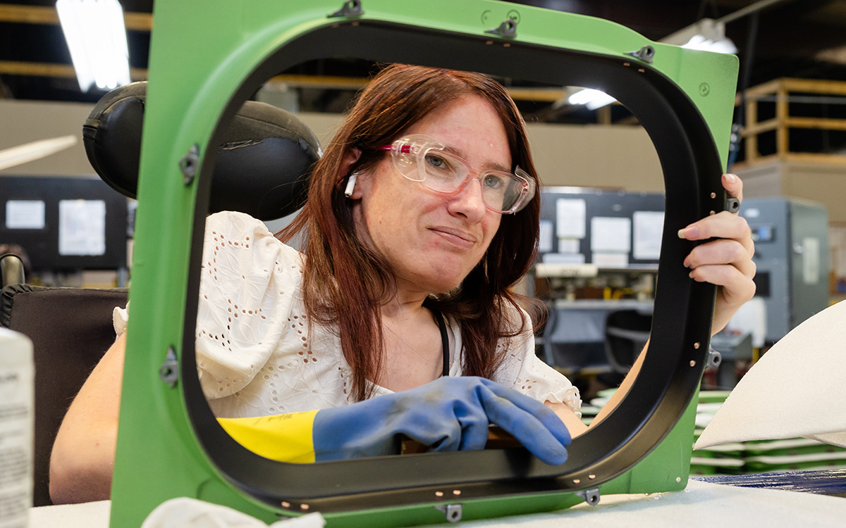 Woman working on airplane window frame.