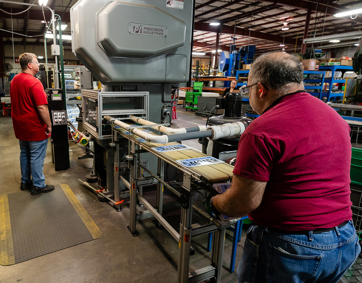 Two men cutting digital license plates