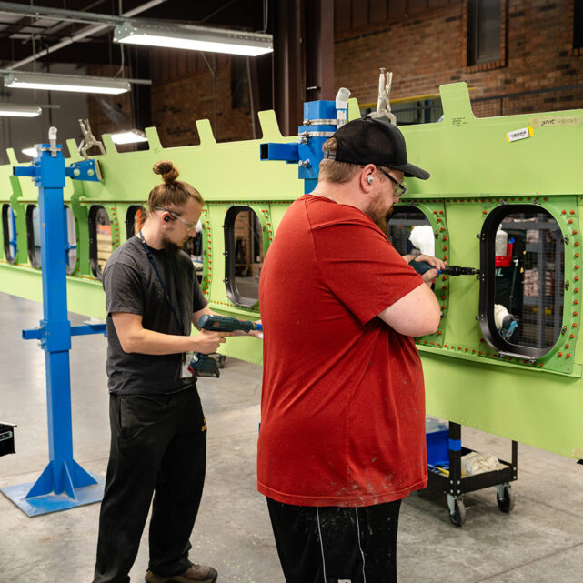 Two men working on aircraft panel